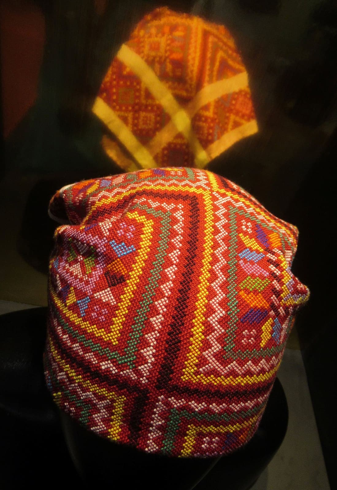 A handwoven Yakan seputangan head cloth in fine geometric bands of pink, green and cream.
